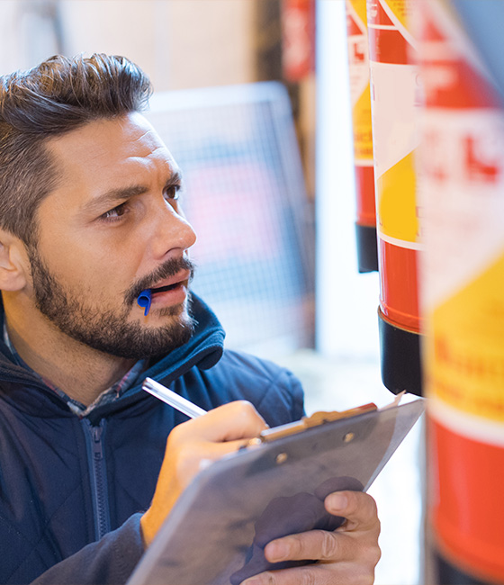 man inspecting fire extinguishers taking notes with clipboard in safety context 14 safety measures 14 compliance reviews