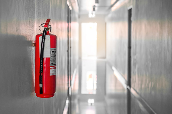 red fire extinguisher mounted on wall in a corridor with light coming from the end of the hall important for safety in buildings with seven floors
