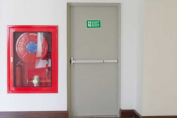 fire extinguisher cabinet next to exit door with green exit sign indicating safety and emergency 5 keys safety measures