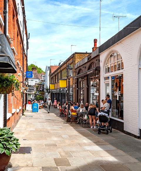 busy street scene with people dining outside on a sunny day showcasing shops and flowers perfect for 7 day experiences
