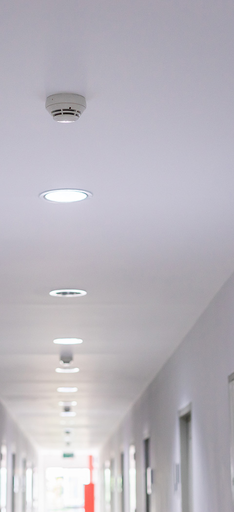 smoke detector on ceiling in a corridor with lights safety feature for six rooms
