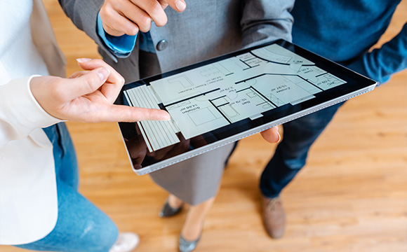 people discussing a floor plan on a tablet showing layout details including rooms and measurements for a project with dimensions related to 11 units