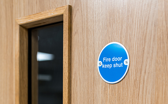fire door sign on wooden door instructing to keep shut for safety and fire prevention