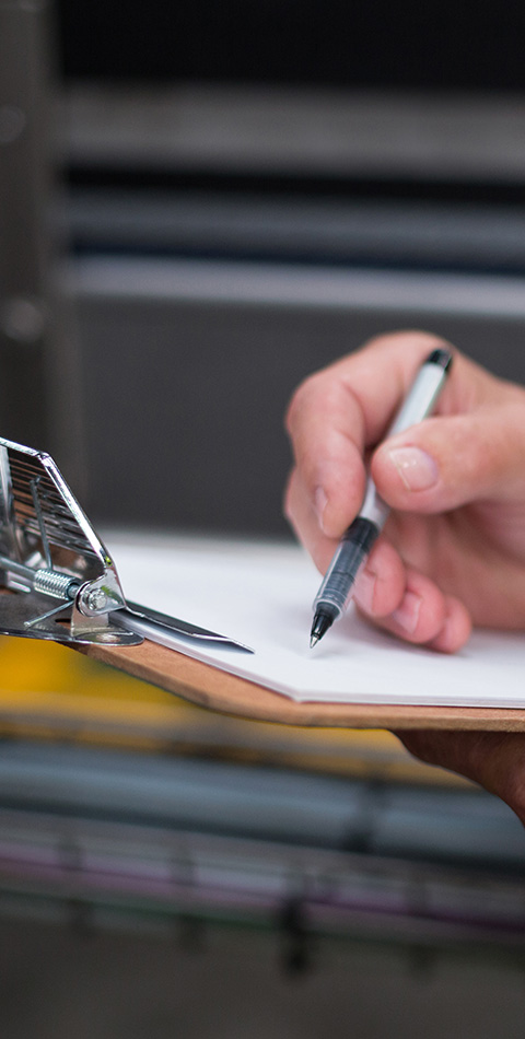 person holding a clipboard with a pen writing notes on paper about 8 important tasks