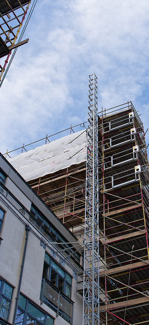 construction site featuring scaffolding on a building with a tower and a cloudy sky showcasing 13 floors in progress