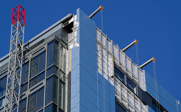 modern building facade construction with crane and blue sky featuring nine panels